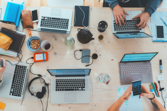 Marketing professionals around a desk utilizing creative marketing tips.