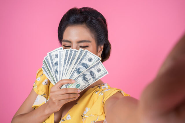 An image of a woman holding money to represent revenue growth.