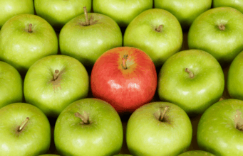 Breaking Free From the Overly Friendly Brand Voice Monoculture Several rows of green apples, with one striking red apple in the center to symbolize how a unique voice can set brands apart from the rest.