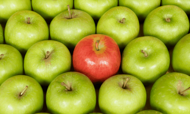 Several rows of green apples, with one striking red apple in the center to symbolize how a unique voice can set brands apart from the rest.