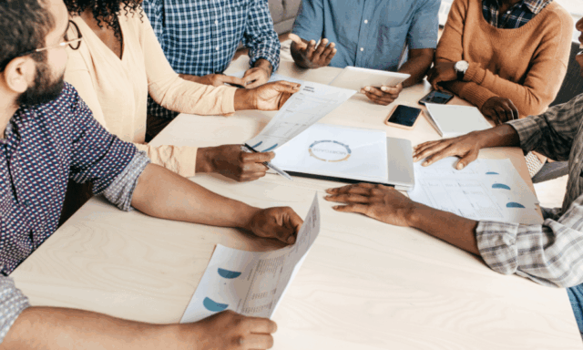 A marketing team holding printouts of metrics, engaged in discussion.