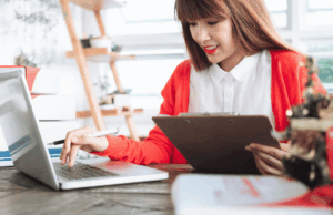 Adaptable or Overstretched? The Hybrid Marketer Dilemma A marketer performs tasks on a laptop while holding a clipboard.
