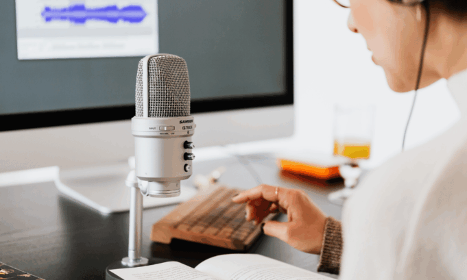 Why Sonic Branding Just Became a Strategic Imperative Marketer recording audio with a microphone while editing sound waves on a computer, representing sonic branding strategy.