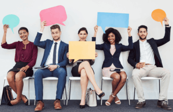 Employee Advocacy for Marketing Teams: Benefits, Strategy, and Best Practices Diverse group of employees holding speech bubbles, representing employee advocacy and employees sharing company and industry content on social media.