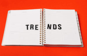 How Marketers Can Bring Trends to Life With Pinterest Predicts An open planner on a bright red background with the word “TRENDS” spelled across its pages in black letters.