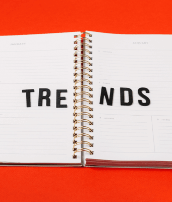 How Marketers Can Bring Trends to Life With Pinterest Predicts An open planner on a bright red background with the word “TRENDS” spelled across its pages in black letters.