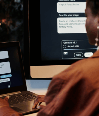 Should Marketers Disclose AI Use? A New Framework Weighs In Person using an AI image generation tool on a laptop and desktop computer to create digital visuals for advertising.